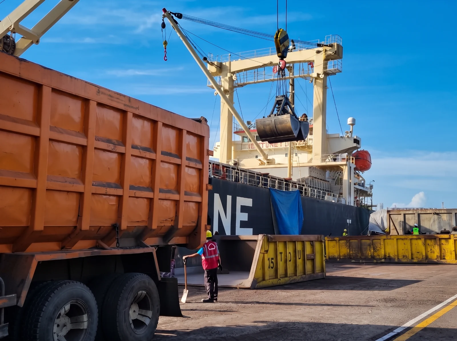 Proses muat palm kernel shell dari truk ke kapal di area pelabuhan.